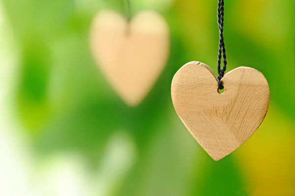 На фото деревянное сердце на зеленом фоне